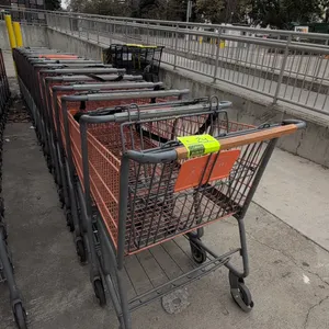 Metal shopping carts. Features orange wire basket with corner bumpers, folding child seat with safety strap, lower wire storage tray, and gray tubular
