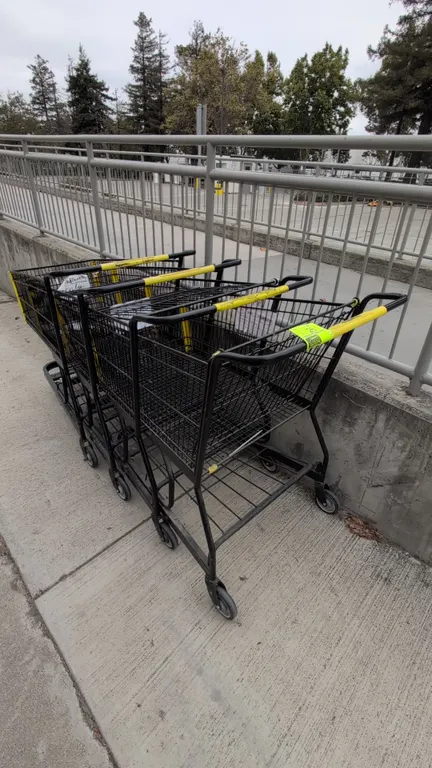 Metal shopping carts. Features black wire basket construction, yellow plastic handle sleeve and corner bumpers, folding child seat, and lower storage