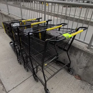 Metal shopping carts. Features black wire basket construction, yellow plastic handle sleeve and corner bumpers, folding child seat, and lower storage 