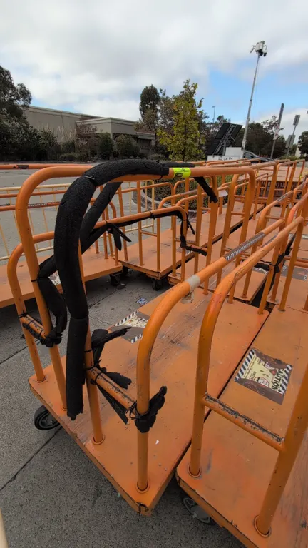 Metal platform lumber carts. Features tubular divider uprights, solid metal platform deck, and orange finish. Dimensions: 54" x 30". Mounted on caster