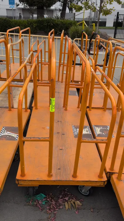 Metal platform lumber carts. Features tubular steel upright dividers and solid platform deck on a steel frame with an orange finish. Mounted on caster