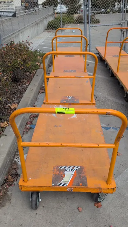 Metal platform carts. Features orange steel platform deck, tubular push handle, and 6-wheel configuration with center wheels and swivel casters. 54"L