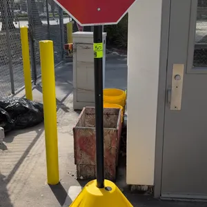 Portable STOP sign with polyethylene rolling base. Features an octagonal reflective stop sign mounted on a black upright pole, yellow molded polyethyl