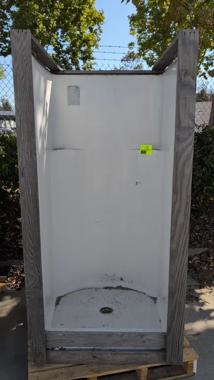 One-piece poly shower stall. Features molded corner shelving and center floor drain opening. Set in wooden exterior framing. Dimensions: 36" x 37" x 7