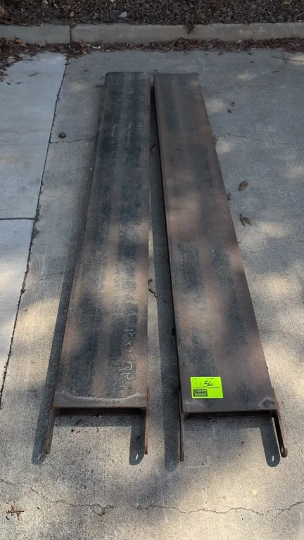 Metal forklift fork extensions. Features steel channel construction with tapered tips and rear pin retaining brackets. Dimensions: 12"W x 100"L.