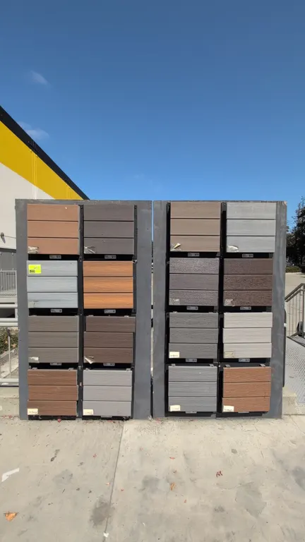 Wood merchandise display stands. Features two painted wood display panels fitted with assorted mounted laminate wood and composite decking samples in
