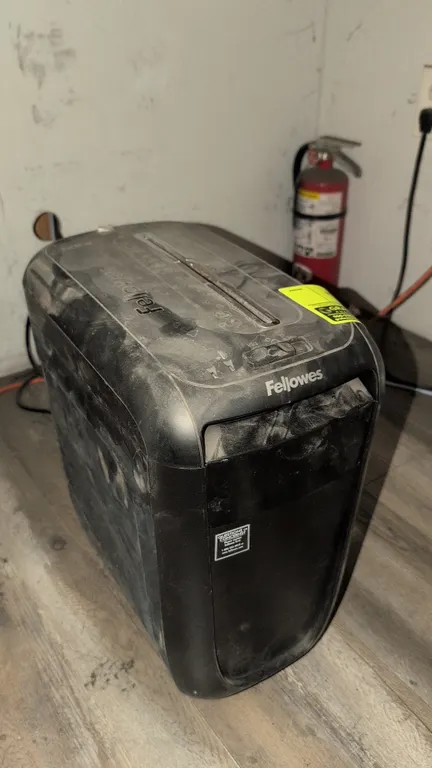 Fellowes paper shredder. Features a top-loading feed slot, pull-out waste bin, forward and reverse controls, and an integrated power cord.
