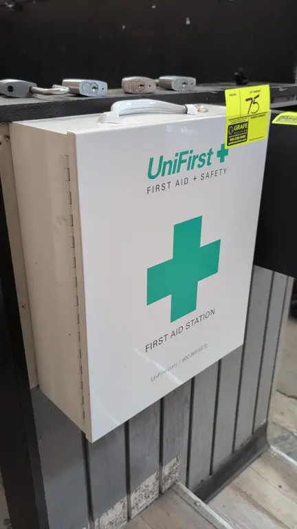 UniFirst metal first aid station cabinet. Features 3 interior shelves, door storage pouch organizer, top carry handle, and latch closure. Includes ass