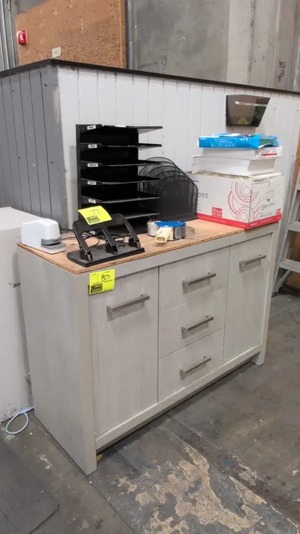 Laminate wood cabinet. Features 2 side cabinet doors, 3 center storage drawers, brushed metal bar pull handles, and an unfinished wood top. 48" x 19"