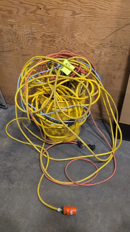 Assorted electrical extension cords and Ethernet cables. Includes heavy-duty yellow and orange extension cords with grounded plugs and connectors, alo