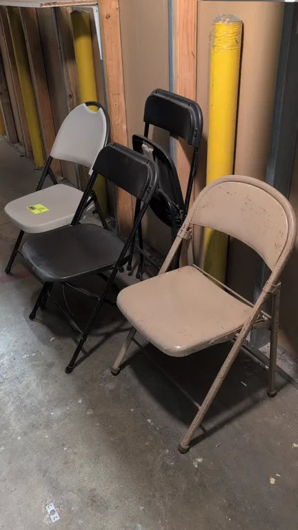 Assorted folding chairs. Includes (2) black plastic folding chairs, (1) gray plastic folding chair with handle cutout, and (1) tan all-metal folding c
