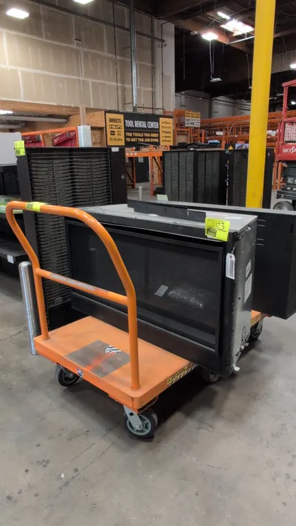 Metal platform cart. Features orange finish, tubular push handle, and a 6-wheel configuration with center rigid wheels and corner swivel casters. 54"L