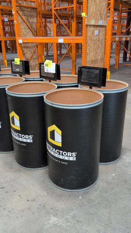 Fiber display barrel with metal rim and sign stand. Features black exterior finish with Contractors' Warehouse graphics and an attached top-mounted me