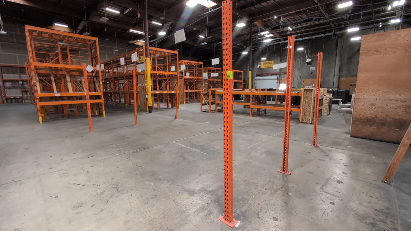 Teardrop pallet racking upright poles. Features steel construction with orange finish, standard teardrop punch pattern, and welded floor mounting base