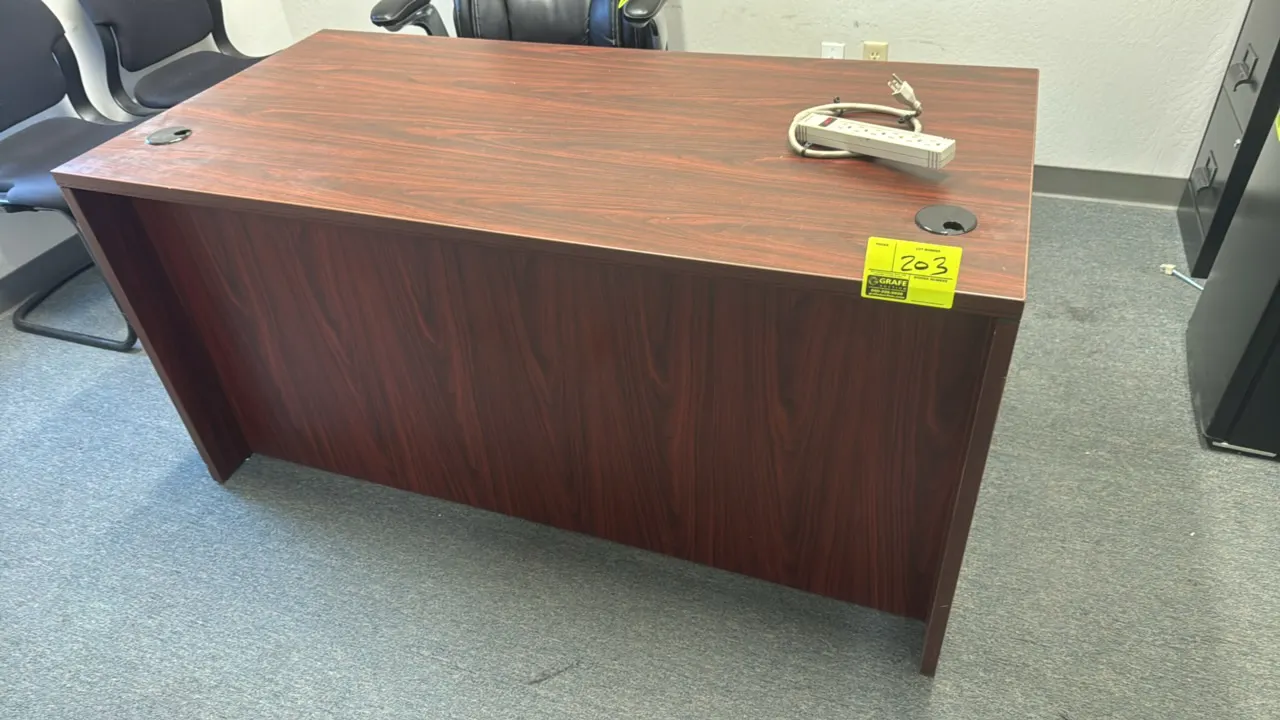 Wood laminate single-pedestal desk. Features a reddish woodgrain finish, right-hand two-drawer pedestal, full modesty panel, and dual desktop cable pa