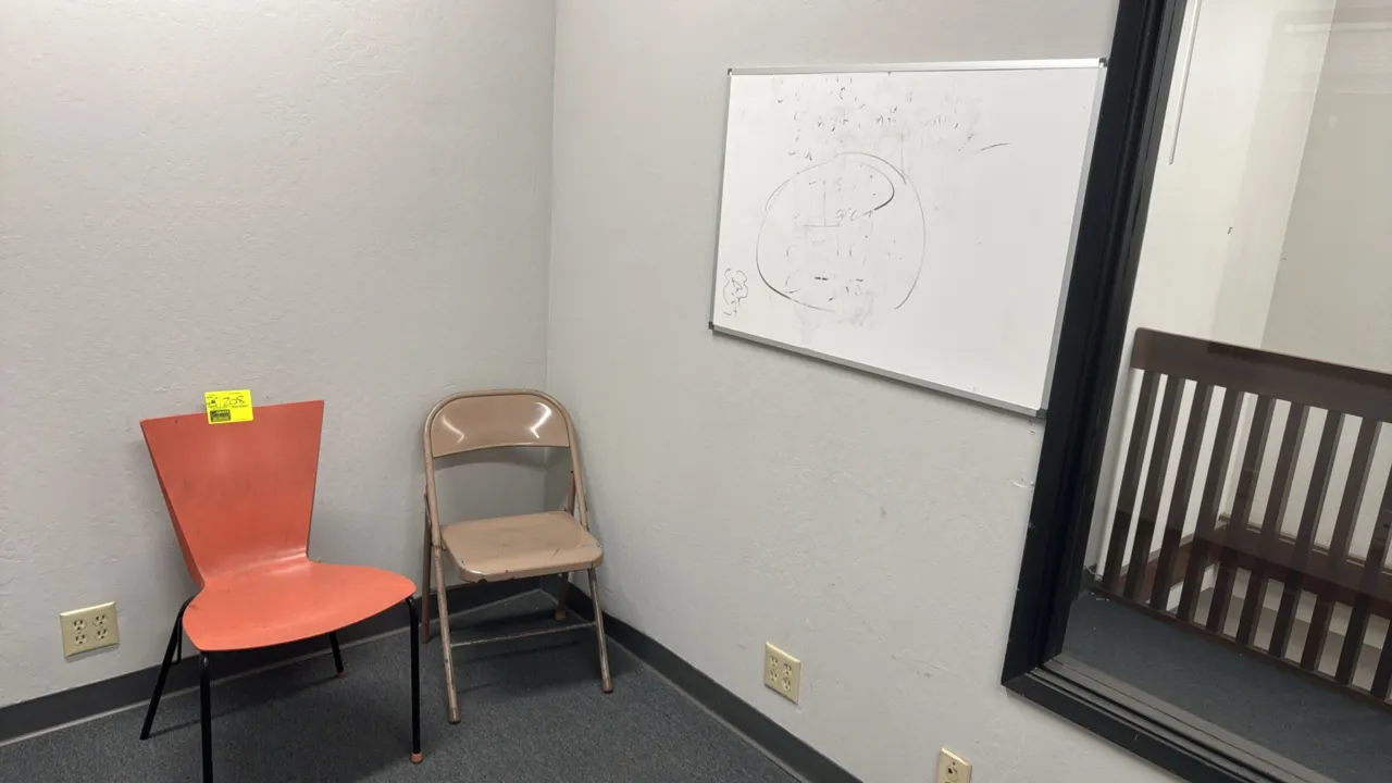 Seating and whiteboard lot. Includes (1) orange molded polypropylene side chair with black metal legs, (1) tan metal folding chair, and (1) 3'x2' dry