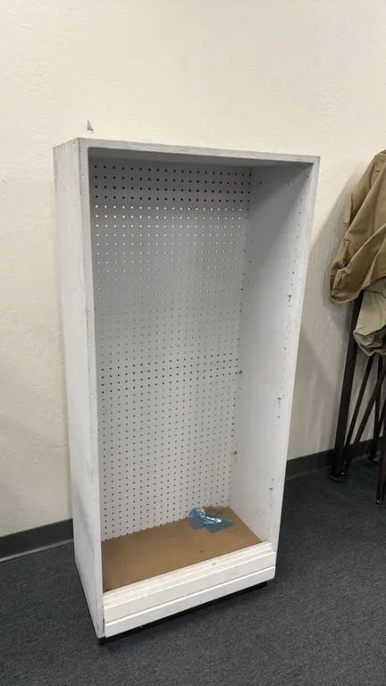 Wood pegboard display merchandiser. Features a white finish, perforated pegboard back panel, and pre-drilled interior shelf pin holes. 24" x 13" x 55"