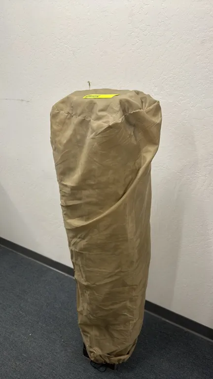 Pop-up canopy tent with folding metal frame and tan fabric cover. Approximately 10' x 10'. Includes matching storage cover bag.