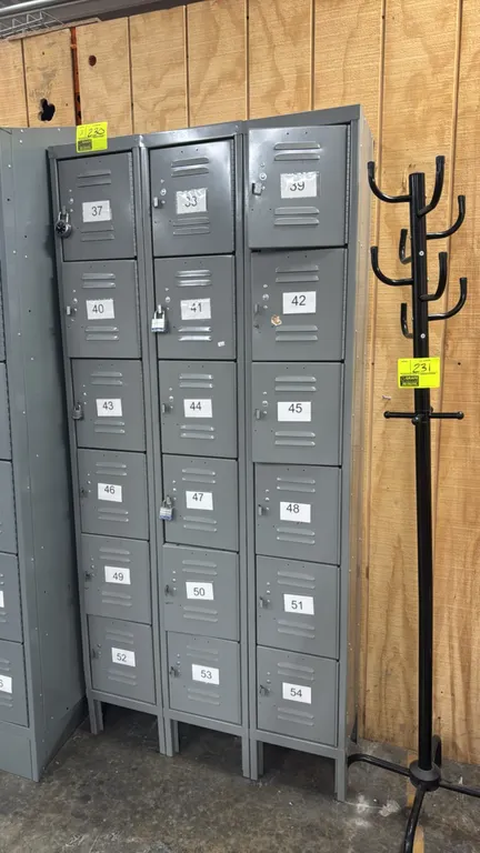Metal locker sections. Features 6-tier compartment design, louvered ventilation doors, padlock hasps, and elevated legs. Gray painted finish. Dimensio