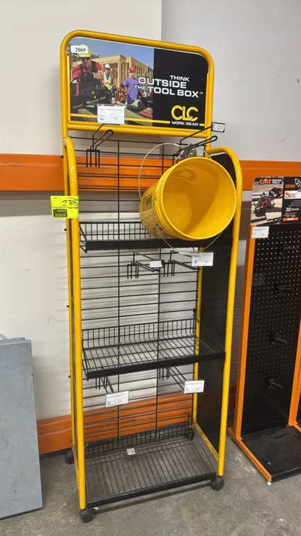 CLC Work Gear metal mobile merchandiser display rack. Features branded header signage, wire basket shelving, display hooks, and attached yellow bucket