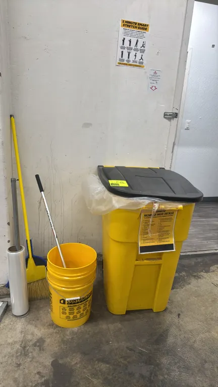 Cleaning and packaging supply package lot. Includes a yellow mobile plastic trash can with hinged black lid, a 5-gallon utility bucket, a bristle broo