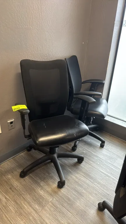 Faux leather mesh-back office chairs. Features padded black faux leather seats, breathable mesh backrests, and adjustable armrests. Mounted on 5-star