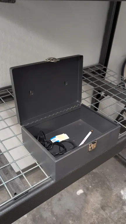 Metal box. Features a hinged lid, front latch closure, and top folding carrying handle. 11"L. Contents not included.