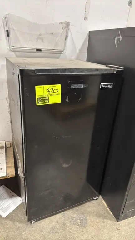 Magic Chef mini refrigerator. Features a single black door, bottom crisper drawer, and in-door storage bins. 33"H. Note: Missing upper interior shelve