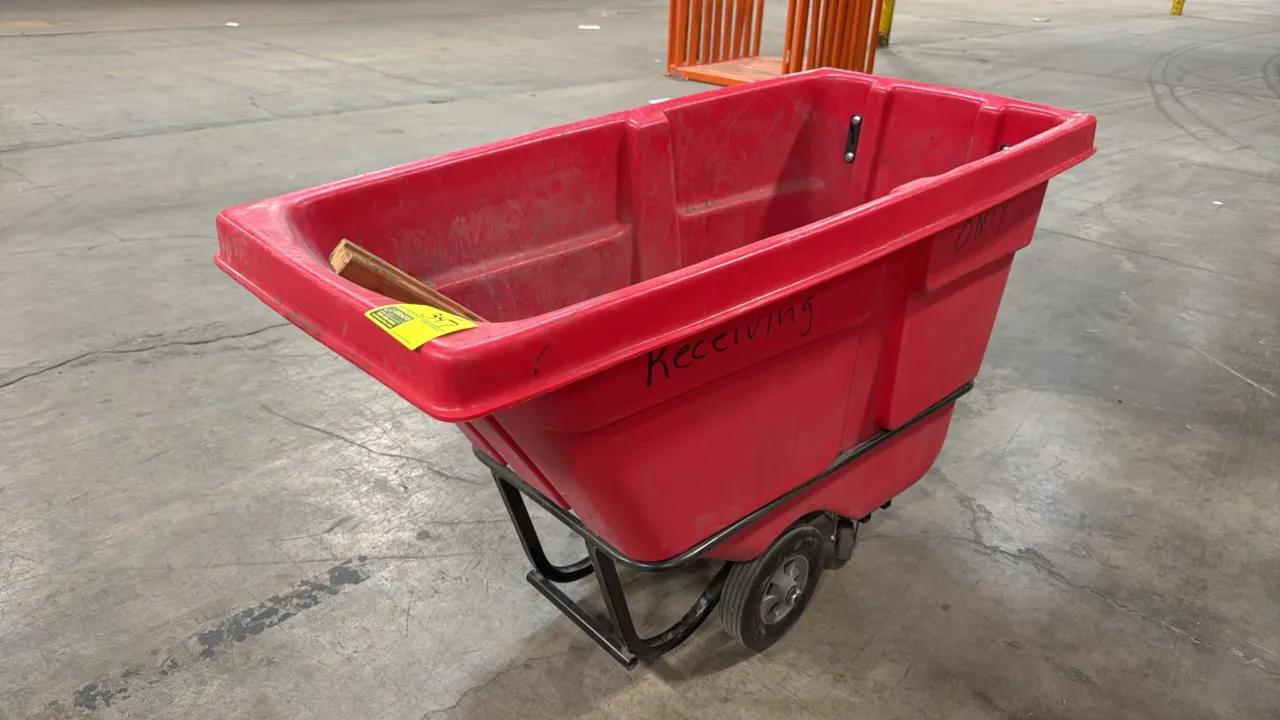 Uline 0.5 cu yd standard tilt truck. Features red molded polyethylene body, tubular steel frame, integrated push handle, two main wheels, and rear swi
