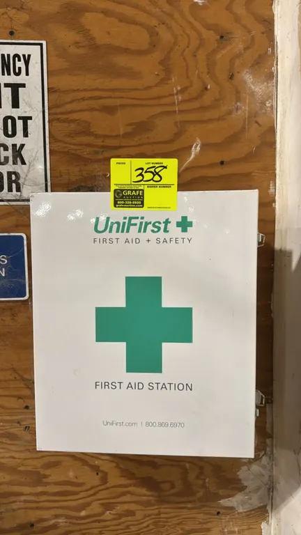 UniFirst metal first aid station cabinet. Features white metal wall-mount construction, single hinged door with latch, 3 interior shelves, and interio