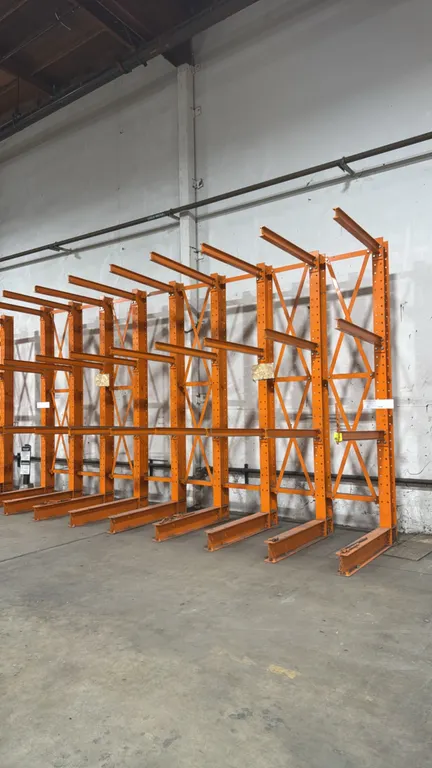 Metal cantilever racking sections. Features structural steel upright columns with bolt-on cantilever arms, integrated base supports, and cross-bracing