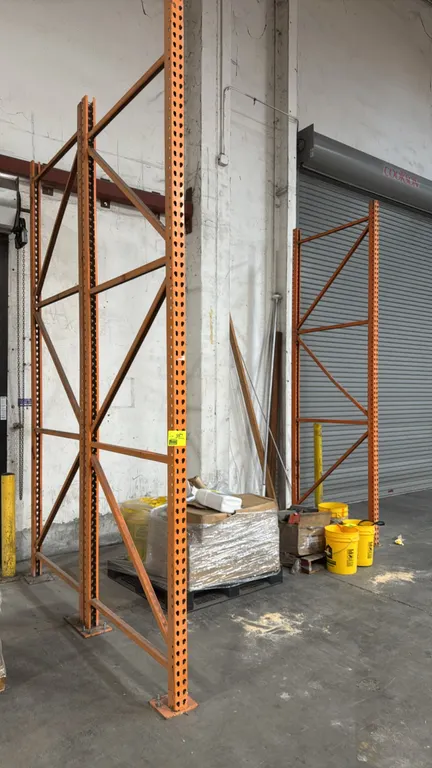 HMH pallet rack upright frames. Features orange steel construction with teardrop punch design and welded footplates. Dimensions: 4'D x 12'H. Pallet an