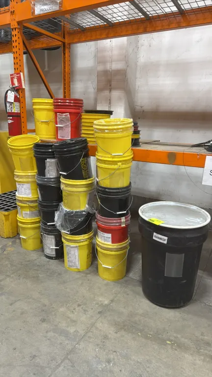 5-gallon poly hazmat buckets and poly drum. Features assorted yellow, black, and red plastic pails with wire bail handles, plastic grips, hazardous wa