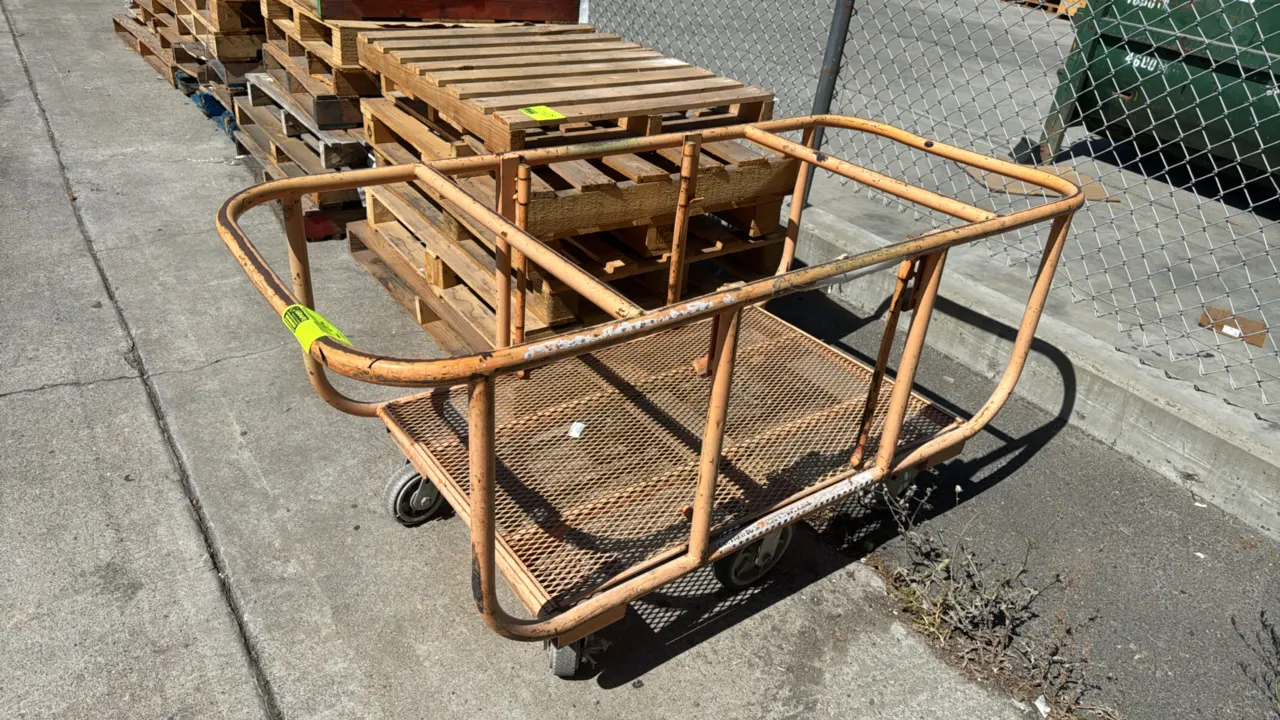 Metal 6-wheel cart. Features tubular steel perimeter railing and expanded metal mesh deck. Dimensions: 69"L x 29"W. Mounted on six wheels with rigid c