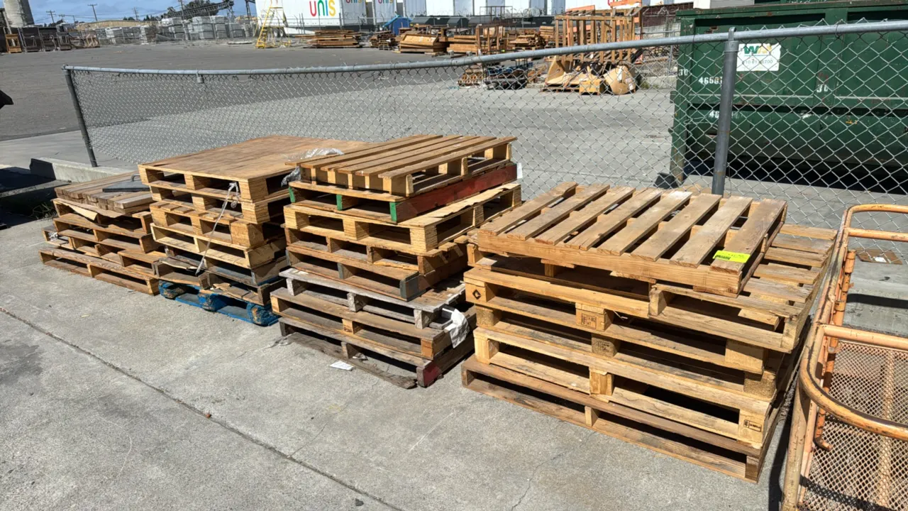 Bulk lot of assorted wooden pallets. Features various sizes, constructions, and deck styles, including slatted and solid top designs. Note: Items show