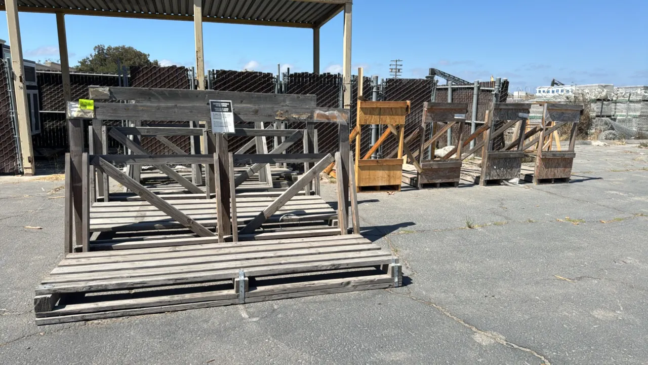 Assorted wooden transport and storage racks. Features various pallet-base A-frame and L-frame structures constructed of dimensional lumber, plywood, a