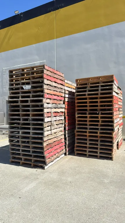 Bulk lot of wooden pallets. Features wood slat deck construction and painted stringers. Dimensions: 4' x 4'.