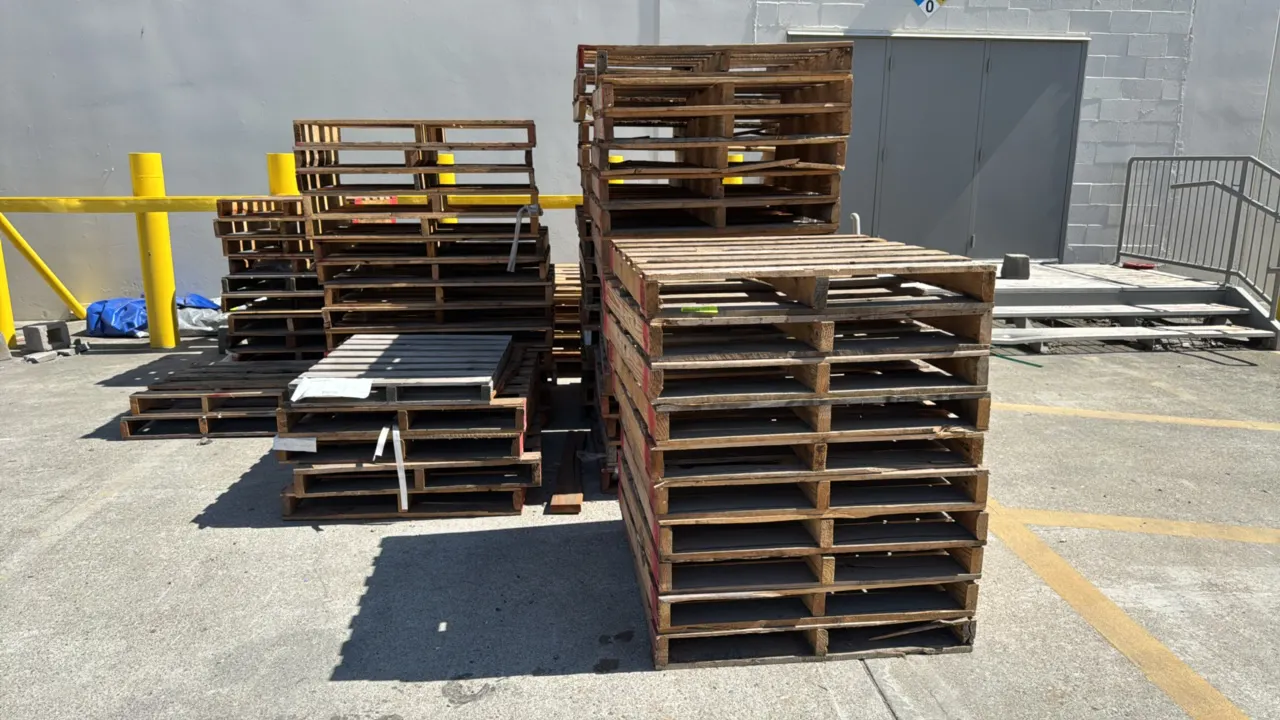 Bulk lot of assorted wooden shipping pallets. Includes various sizes and styles in stacked configurations. Note: Blue plastic pallets and surrounding