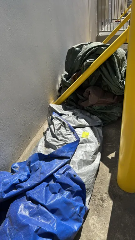 Bulk lot of assorted utility tarps. Includes multiple woven polyethylene tarps in green, silver, blue, and brown. Features folded reinforced hems with