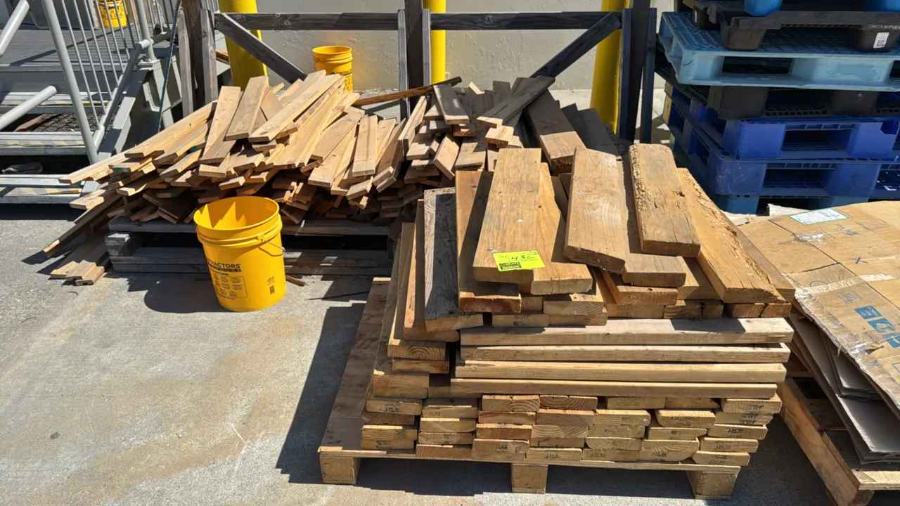 Assorted wood pieces and lumber. Features various lengths, widths, and cuts of dimensional wood boards and planks. Note: Yellow buckets and surroundin