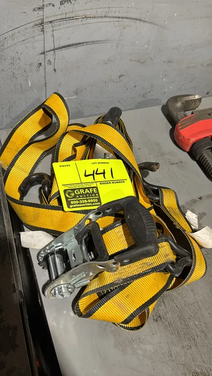 Ratchet tie-down straps. Features yellow webbing with black reinforced edges, ratcheting tension mechanisms with molded handles, and coated steel doub