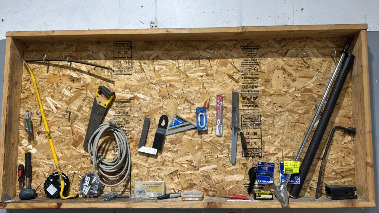 Assorted tools with wooden wall-mount storage rack. Includes DeWalt wrecking bar, Stanley hand saw, rubber mallet, circular saw blades, Empire square,