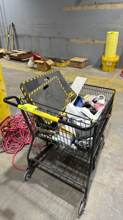 Metal wire shopping cart with assorted contents. Includes (2) CLC foam kneeling pads, portable tool caddy, engine recoil starter assembly, Multiquip m