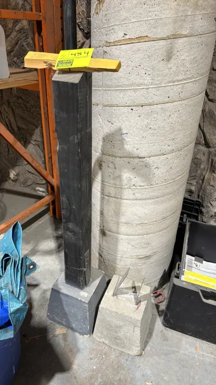 Wood post with concrete pier bases. Includes (1) black painted wood post mounted to a concrete base with a metal bracket, and (1) concrete pier base w