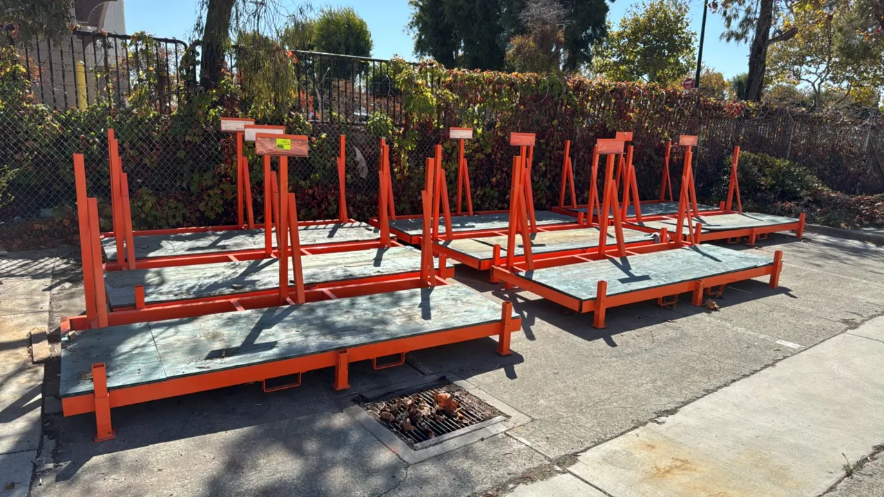 Metal slab storage racks. Features steel frame construction with orange finish, vertical upright supports, plywood decking, and integrated forklift po