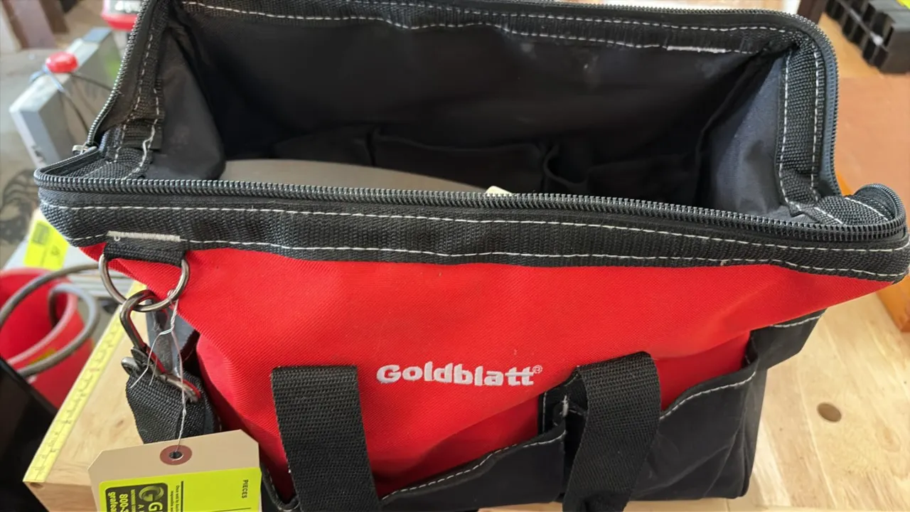 Goldblatt tool bag with assorted masonry hand tools. Includes masonry brush, 11" x 5-1/2" trowel, clamps, and related accessories. Bag features heavy-