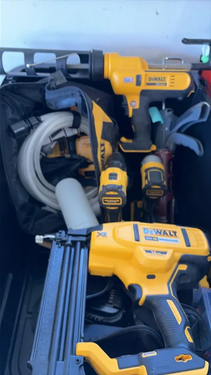 DeWalt 20V cordless tool assortment with tote. Includes an 18-gauge brad nailer, caulking gun, (2) drills/drivers, batteries, tool bag, and QuicStick