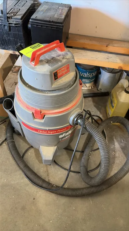 Shop-Vac QSP 8-gallon wet/dry vacuum. Features a 2.0 peak HP motor, top carry handle, flexible hose, and rear accessory storage. Mounted on casters.
