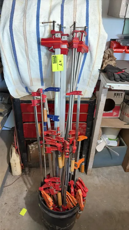 Assorted woodworking bar clamps. Features various styles and lengths including steel F-clamps, aluminum bar clamps, and parallel jaw clamps with woode