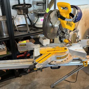 DeWalt sliding compound miter saw. Features sliding rails, rotating miter table, blade guard, and dust collection port. Includes folding miter saw sta